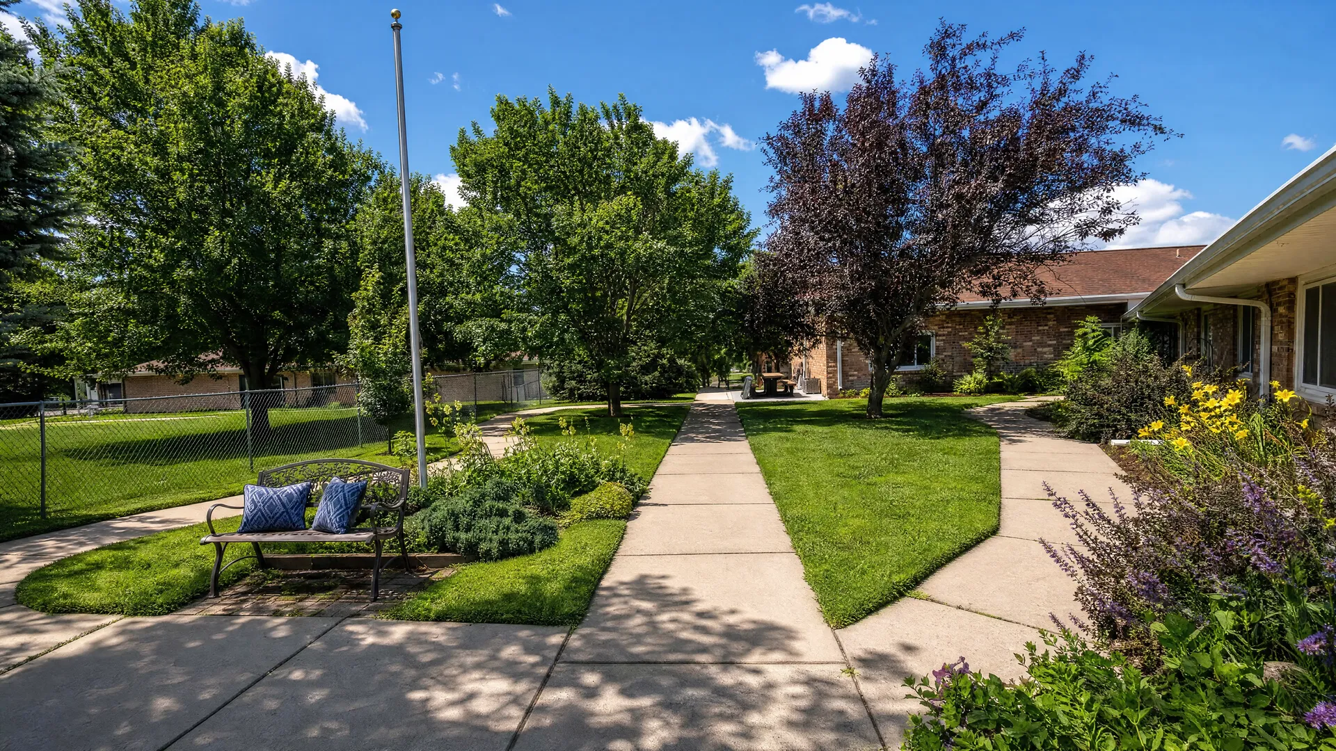 Courtyard garden with a shaded bench and walkways at Nora Springs Care Center