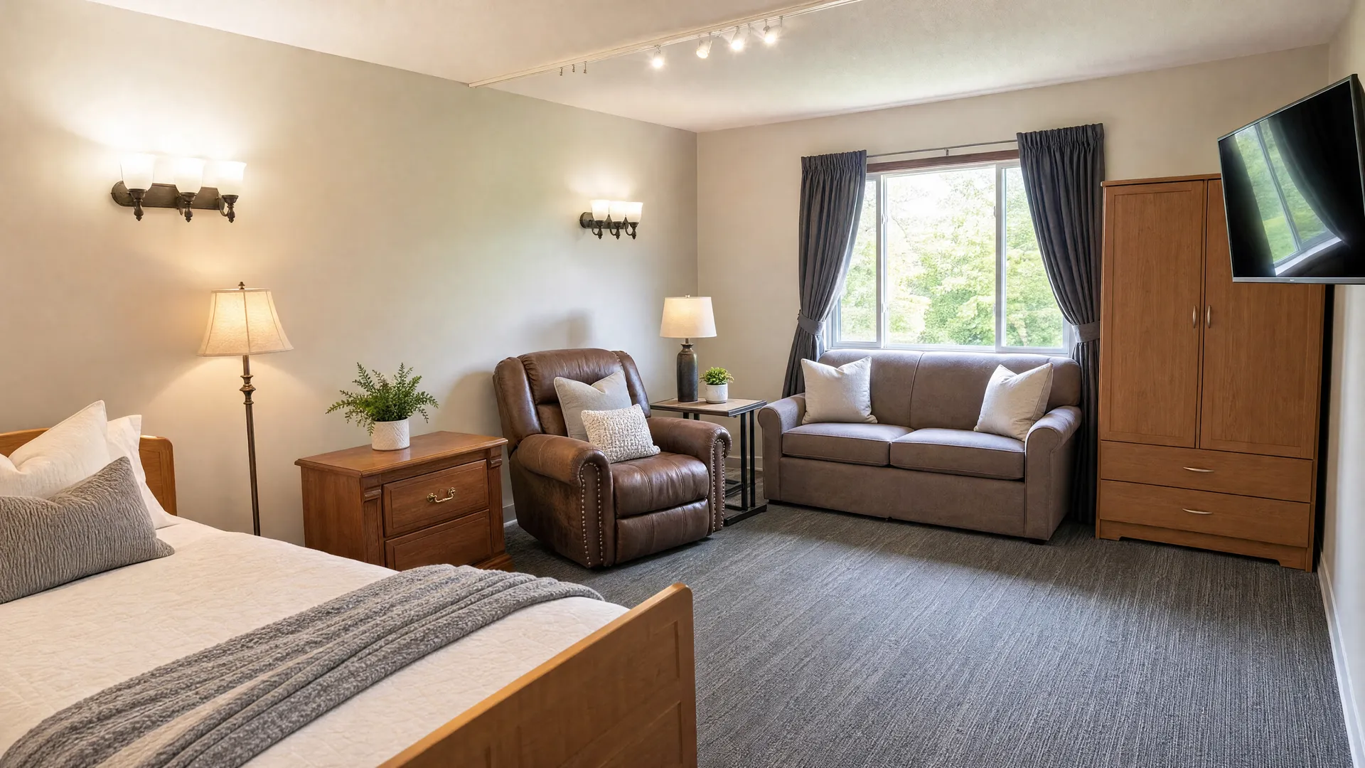 Private resident room with a bed, loveseat, recliner and television at Nora Springs Care Center